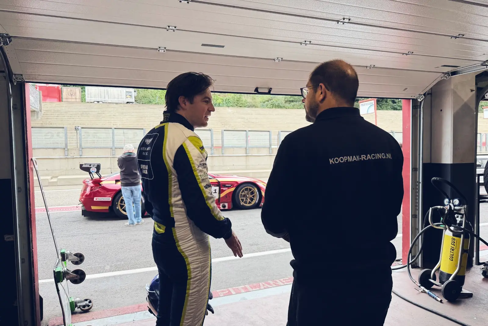 Jamie Vandenbalck in overleg met Koopman Racing in de pitbox van Circuit Zolder, met de BMW M6 GT3 op de achtergrond